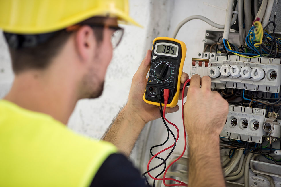 An electrician uses a multimeter to measure voltage on circuit terminals