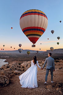 Braut und Bräutigam sehen sich Luftballons an und stehen in freier Landschaft