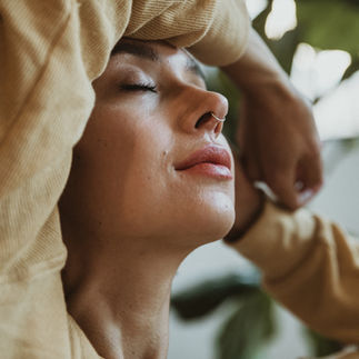 Woman with eyes closed, enjoying sunlight, serene moment, peaceful expression, healthy glow.