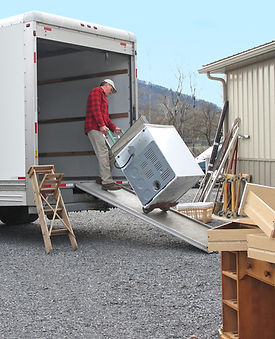 Man pulls dryer onto moving van using a dolly