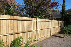 a traditional wooden closeboard fence installed outdoors along a gravel garden path