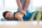 Massage therapist giving back massage to young woman. Patient lying on massage table