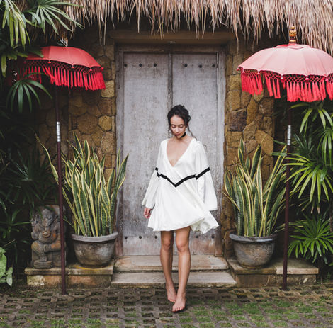 Young woman in white tunic in front of a traditional house in Bali