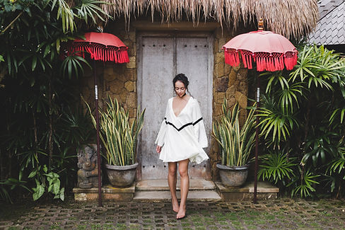 Young woman in white tunic in front of a traditional house in Bali