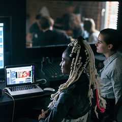 Two women working in a recording studio with computer screens and equipment.