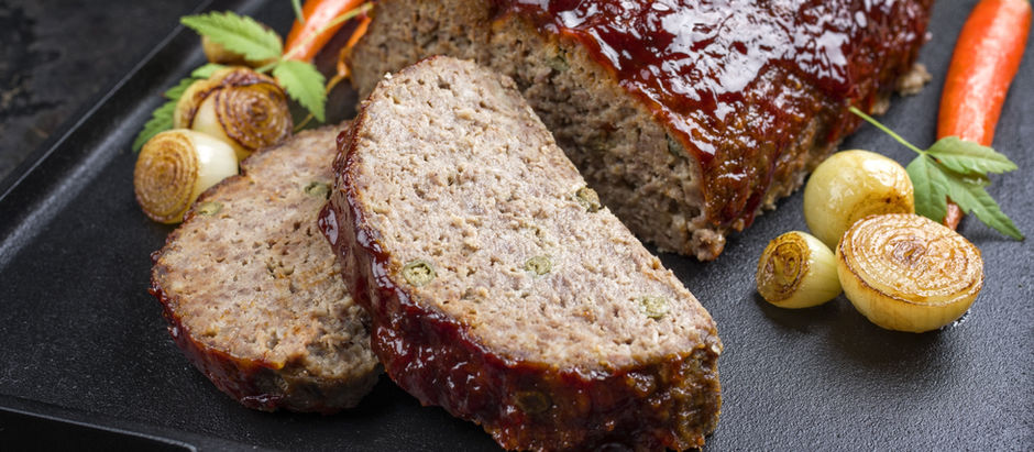 Golden-brown meatloaf with a ketchup glaze served alongside roasted carrots and caramelized onion wedges on a sheet pan—Southern-style comfort food inspired by Brandon, Florida.