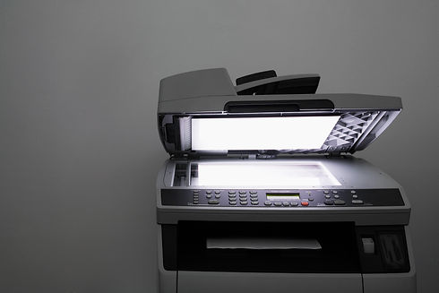 An office photocopier with an open scanner lid scanning a document on the glass bed