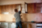 A man measures the height of kitchen cabinets