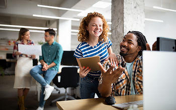 Two diverse coworkers, a man and a woman, happily collaborating in a vibrant office setting, reflecting a workplace that aligns with the principles of Employment Equity Compliance as discussed in the article titled 'Achieving Employment Equity Compliance: Aligning Organisational Structure with Regulatory Requirements'.