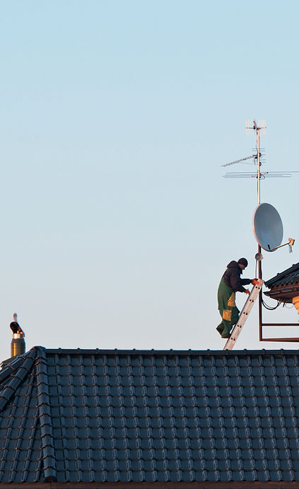 Photo of a male on a ladder installing satellite dish
