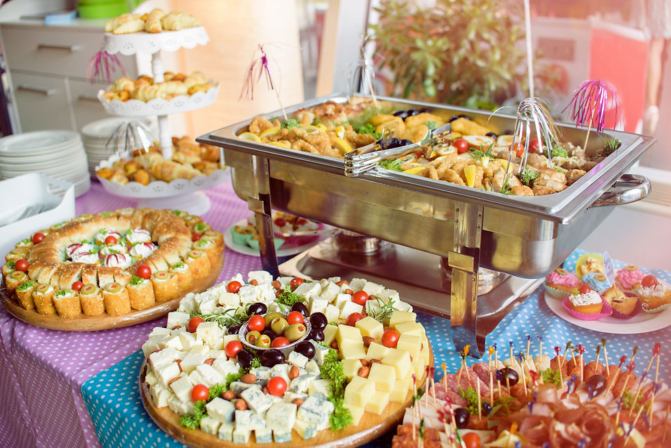 Catered party buffet table with cheese boards, appetizers, and a chafing dish