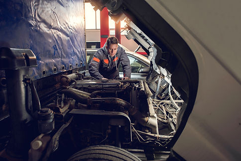 Auto mechanic working on a truck engine bay with a bright work light in a repair shop