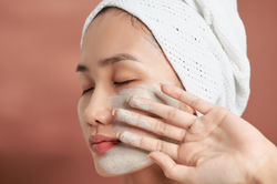 Asian woman applying facial clay mask