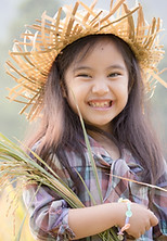 A girl wearing a straw hat holding rice paddy