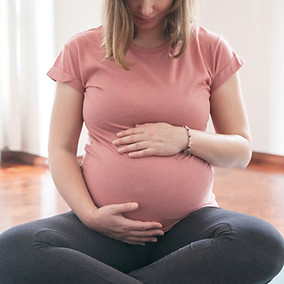 a pregnant woman sitting cross-legged, holding her bump