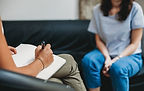 Personne qui écrit sur sa tablette en écoutant une autre personne parler
