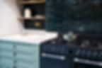 Contemporary kitchen design featuring a dark colored range cooker, light countertop, sage