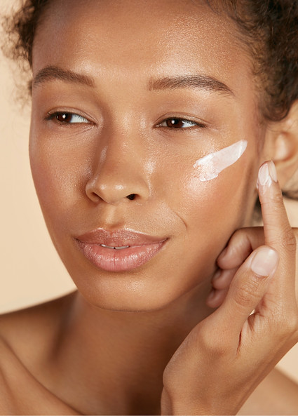 close up of a young woman applying face cream