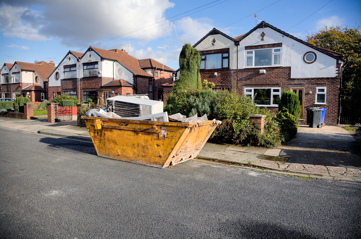 A yellow skip full of residential waste placed outside the house