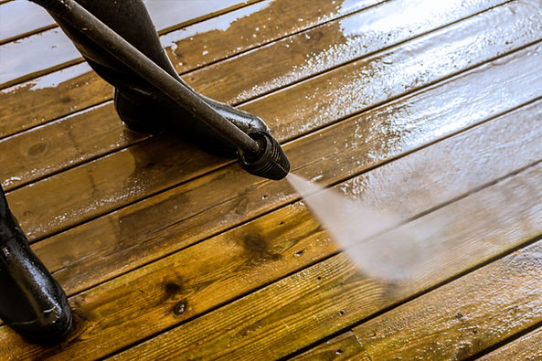 Pressure washing a wooden deck to remove dirt and algae.