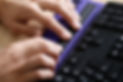Blind person using computer with computer display and a computer keyboard. 