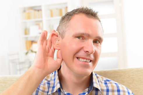 Smiling man pointing to a nearly invisible hearing aid fitted in his ear