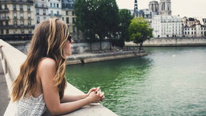 Woman looking out over a bridge, thinking