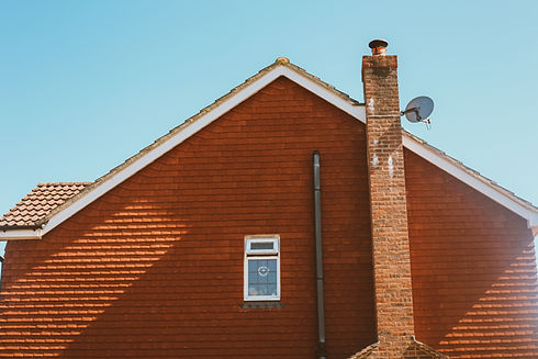 A suburban house with a red tiled exterior and a steep gabled roof