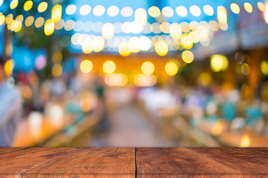 Image of wooden table in front of abstract blurred restaurant lights background
