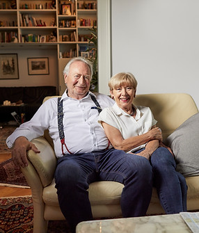Ein älterer Herr und eine Dame sitzen gemütlich in einem Wohnzimmer, symbolisiert Unterstützung bei Alltagsorganisation und persönlichen Anliegen.