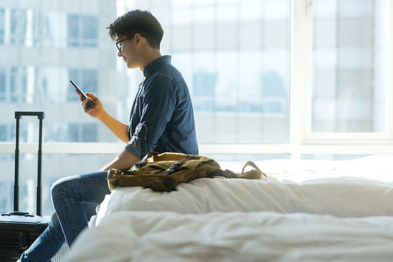 Person Sitting On Bed Looking At Smartphone