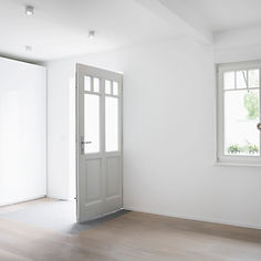 Empty interior room with white walls, high ceilings, and natural light