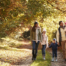 Familie mit drei Kindern spaziert im Herbst Wald