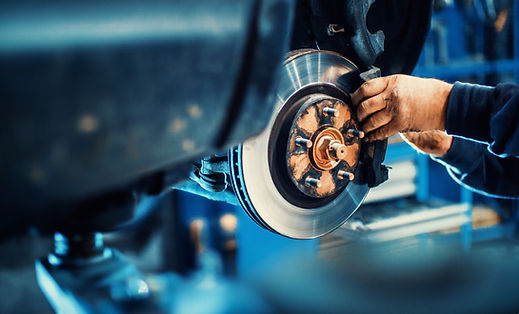 Mechanic using tools to install a brand new brake disc rotor assembly on a vehicle axle