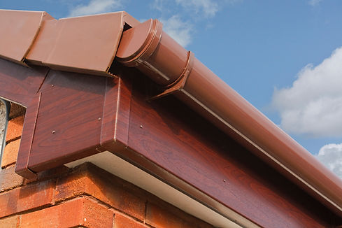 A brown plastic gutter system attached to a building's corner