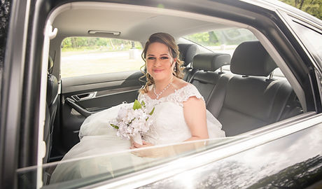 A beautiful bride with a flower bouquet is sitting in a stylish car for wedding transport