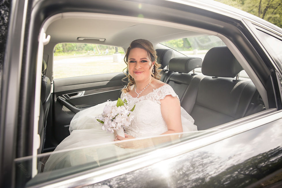 Bride in a white dress looking out the window of a wedding taxi in Bideford UK