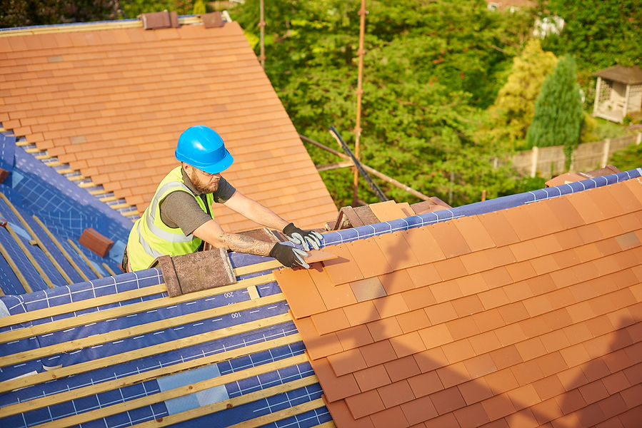 a roofer nails on the roof tiles