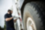 A man inspects a large truck tire