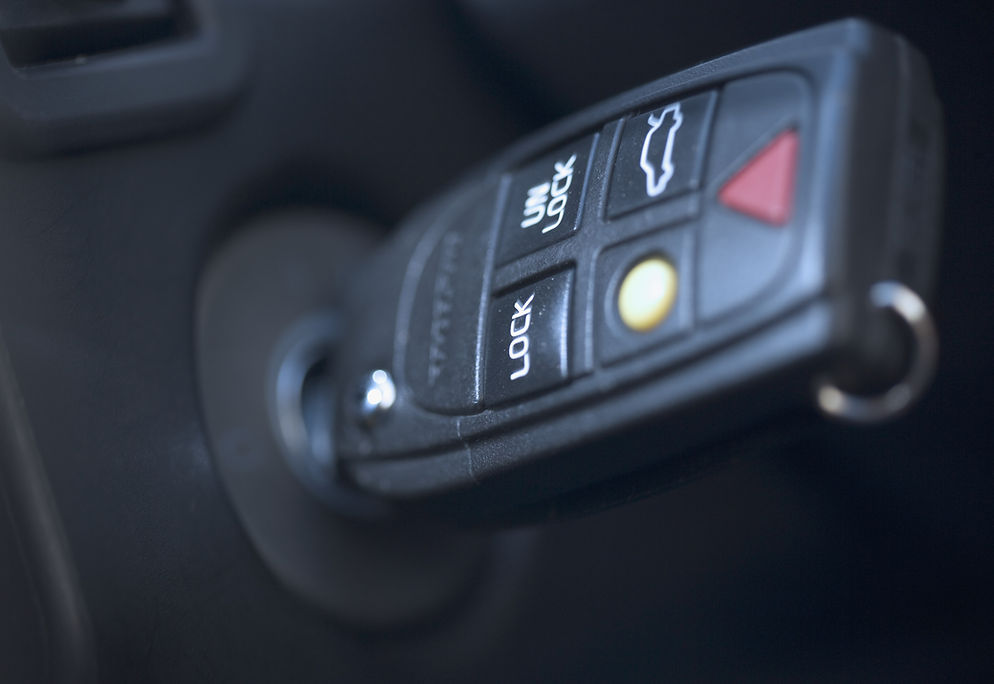 A close-up of a car key inserted into an ignition with visible buttons for lock