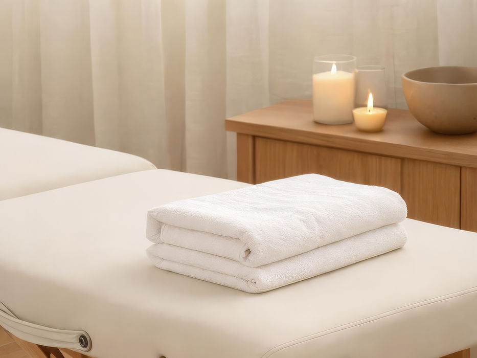 Massage table with folded white towels and lit candles