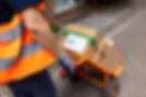 Close-up of a female courier worker moving the parcel boxes on a cart outdoors for deliver