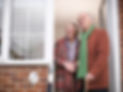 Senior couple looking up from front door of home