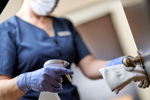 Office cleaner disinfecting office door handle using green products.