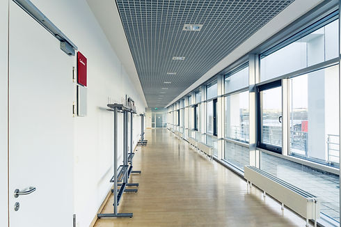 White corridor with wooden floor, big windows and entrances to the conference rooms