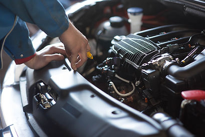 Mechanic's hand checking oil dipstick under open car hood