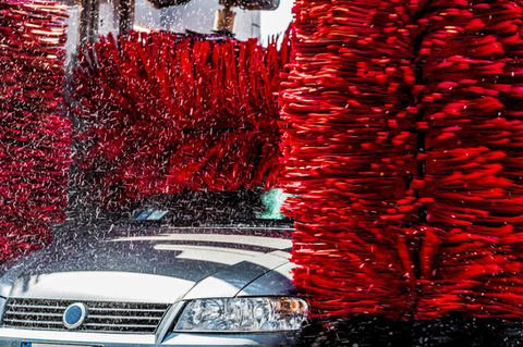 Car in automatic car wash with red brushes