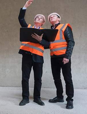 Two men wearing safety vests and inspecting the structure of a property