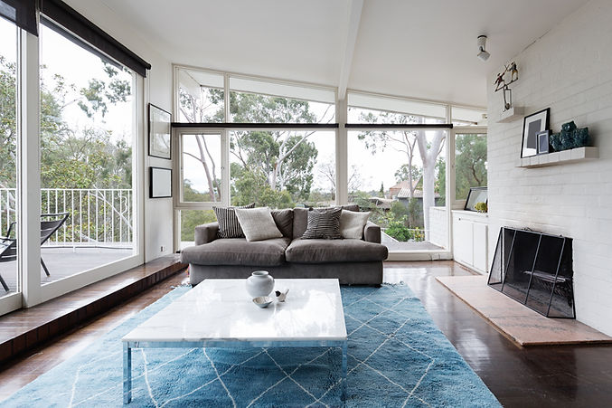 Ladybird Conveyancing - Buying a property with an instant quote - calculating transfer (stamp) duty and associated government fees. Family living area with large open widows viewing native trees and a clean style with a gaurded off fire place.