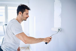 Man painting a light blue wall with a roller